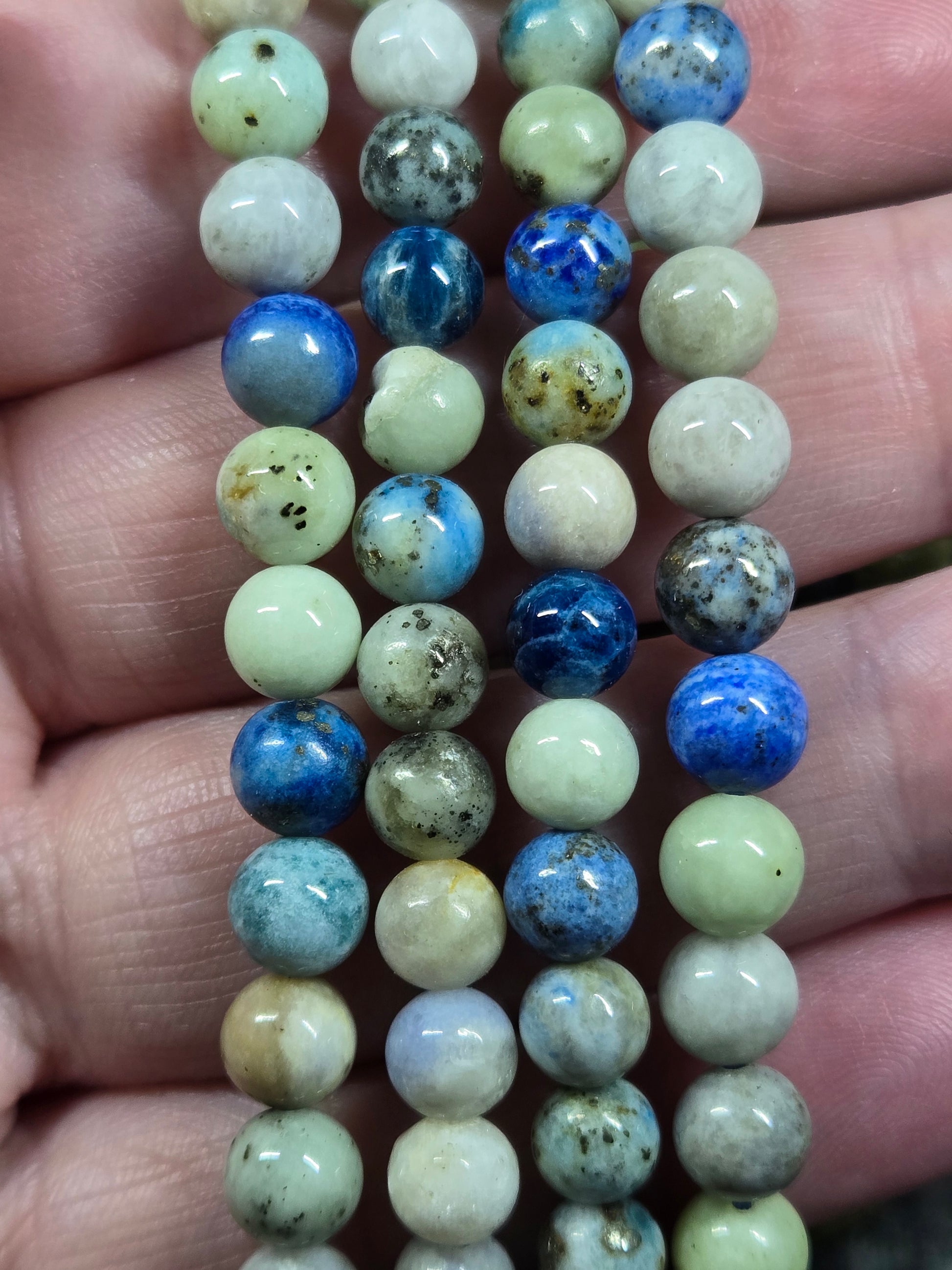 Azurite, hackmanite and chrysocolla crystal/mineral beaded bracelet being held on 4 fingers to represent size