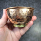 Hand holding a small copper bowl against a dark textured background - Dark Star Curiosities