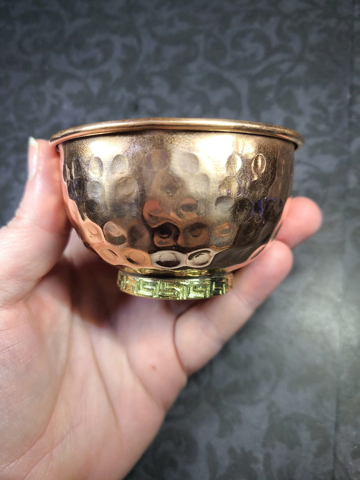 Hand holding a small copper bowl against a dark textured background - Dark Star Curiosities
