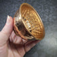 Hand holding a copper bowl with textured interior against a dark patterned background - Dark Star Curiosities