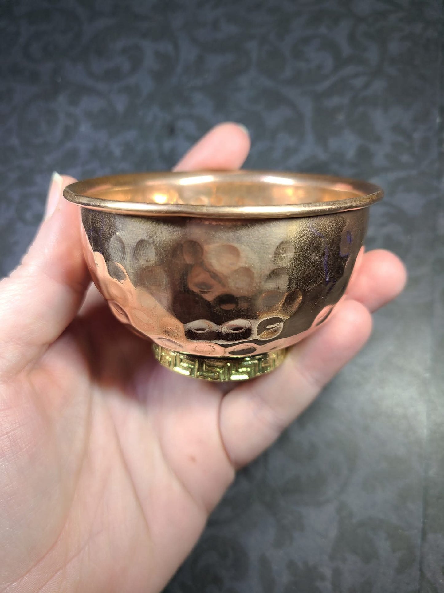 Hand holding a small copper bowl against a dark textured background - Dark Star Curiosities