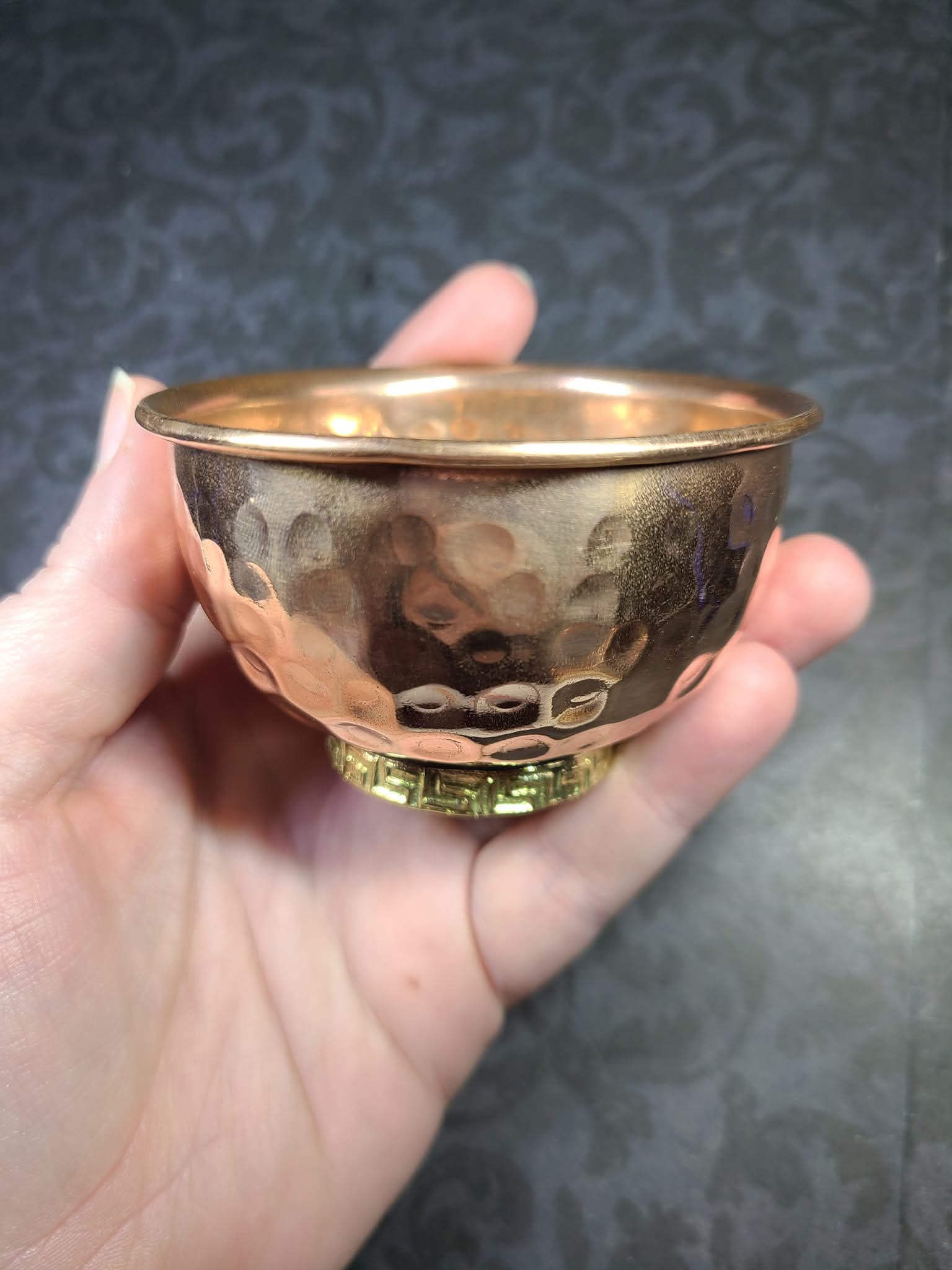 Hand holding a small copper bowl against a dark textured background - Dark Star Curiosities
