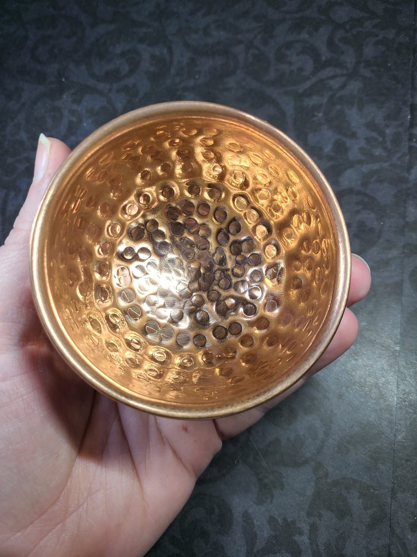 Hand holding a copper bowl with textured surface against a dark background - Dark Star Curiosities