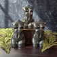 Three pyrite feminine goddess body carvings surrounded by green ferns against a black slate background. 